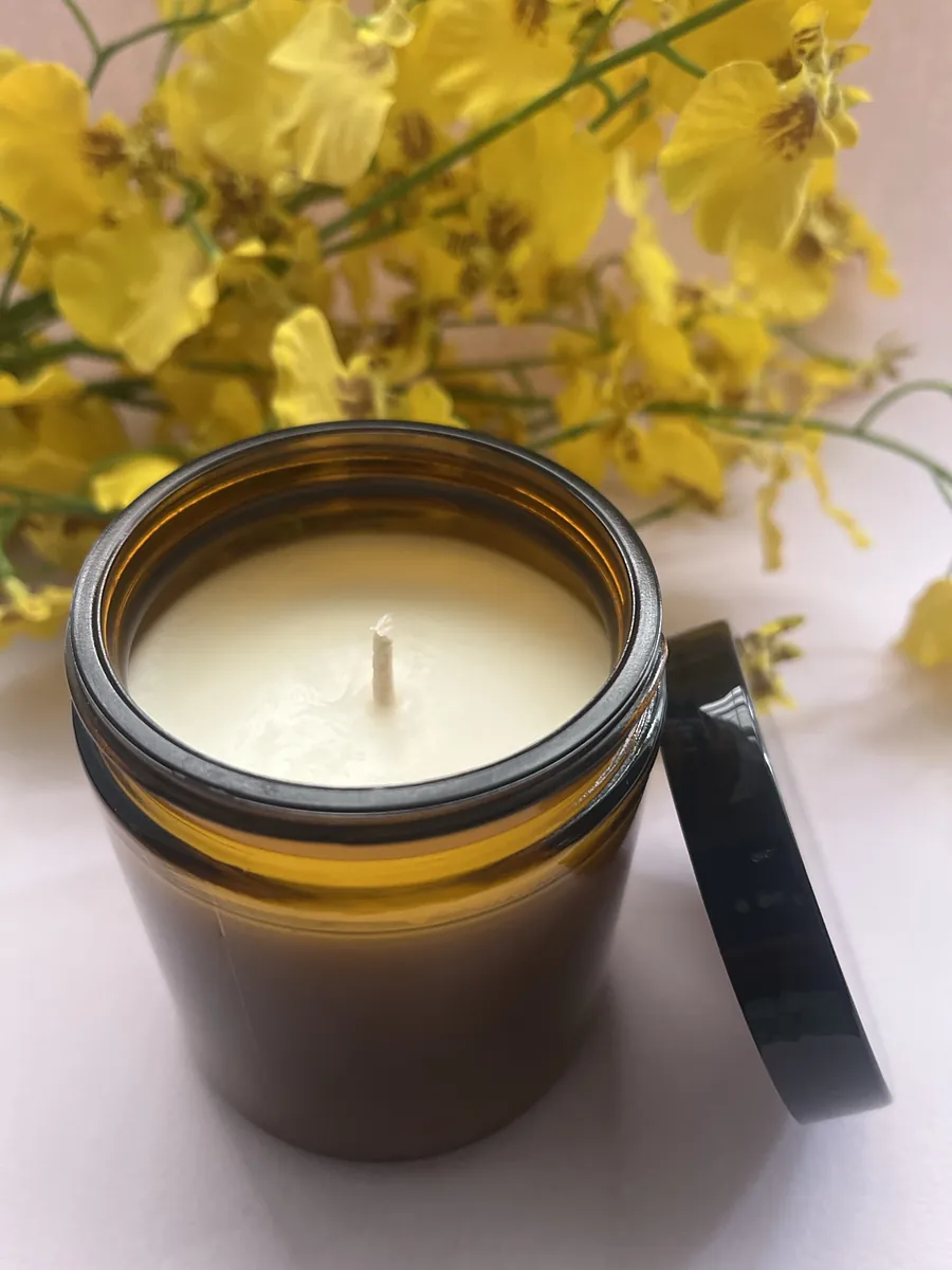 Classic candle in an amber glass jar with its lid